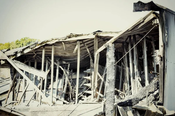 Damaged industry supermarket after arson fire with burn debris of twisted metallic wood structure after intense burning fire disaster ruins waiting for investigation for insurance. Saturated contrasting colors effect dramatic atmosphere