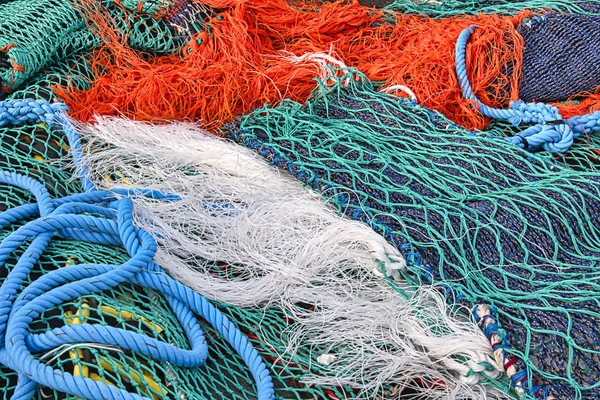 Close up view of colored ropes and nylon nets used to fish. Abstract image of maritime equipment in a port. Detail of pattern of colorful fishnets.