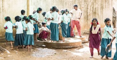Puducherry, Tamil Nadu, Hindistan - Aralık yaklaşık, 2018. Yemeden önce kuyu onların plaka temizlemek için tanımlanamayan zavallı sınıf çocuklarla üniformalar kuyruk açık havada. Öğle yemeği zamanı, genel hükümet okulda sağlıksız gıda