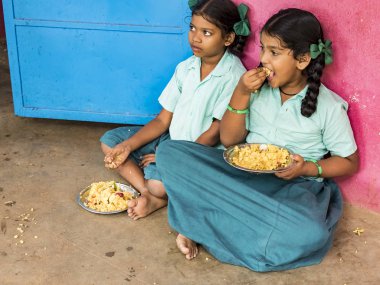 Puducherry, Tamil Nadu, Hindistan - Aralık yaklaşık, 2018. Bazı masala ile pirinç onların sağ eli ile yemek tanımlanamayan zavallı sınıf kızlarla yerde açık havada üzerinde oturan üniformalar. Öğle yemeği zamanı, genel hükümet okulda sağlıksız gıda