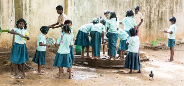 Puducherry, Tamil Nadu, Hindistan - Aralık yaklaşık, 2018. Yemeden önce kuyu onların plaka temizlemek için tanımlanamayan zavallı sınıf çocuklarla üniformalar kuyruk açık havada. Öğle yemeği zamanı, genel hükümet okulda sağlıksız gıda