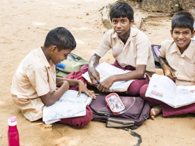 PUDUCHERRY, İNDİA - Aralık 2018. Kimliği belirsiz çocuklar, gençler, devlet okulundan arkadaşlar, yerde oturuyorlar, dışarıda kitaplarla çalışıyorlar..