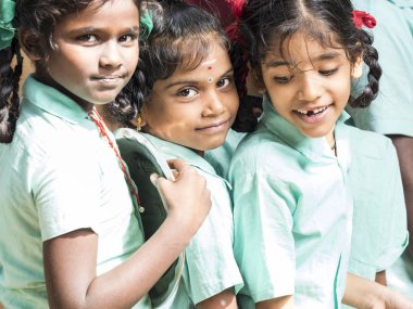 Puducherry, Hindistan - Aralık yaklaşık, 2018. Kimliği belirsiz en iyi çocuk kız arkadaş sınıf hükümet okul kantin için plaka çağrısı ile gülümseyen gülen ayakta üniformalar. Dostluk zevk çok ırklı schoolchilds portresi.