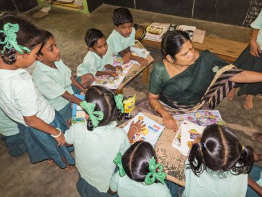 Puducherry, Hindistan - Aralık yaklaşık, 2018. Katta oturan, kapalı kitap okumak sınıf öğretmen ile eğitim devlet okul üniformalı tanımlanamayan mutlu sınıf arkadaşları. Dostluk duygu zevk okul çocuk portresi.