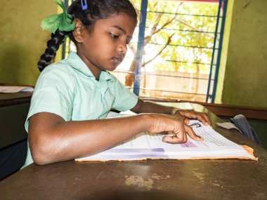 PUDUCHERRY, İNDİA - Aralık 2018. Tanımlanamayan, devlet okulu üniformalı, sandalyeye oturmuş kapalı alanda kitap okuyan ciddi sınıf arkadaşları. Okul gençlerinin portresi.