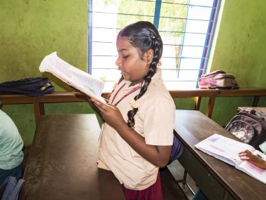 PUDUCHERRY, İNDİA - Aralık 2018. Tanımlanamayan, devlet okulu üniformalı, sandalyeye oturmuş kapalı alanda kitap okuyan ciddi sınıf arkadaşları. Okul gençlerinin portresi.