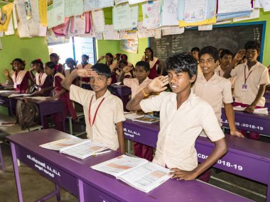 Puducherry, Hindistan - Aralık yaklaşık, 2018. Hükümet okulda tanımlanamayan konsantre ciddi sınıf arkadaşları üniformalar sınıf kapalı kitap okumak okuyan öğretmen, karşılama sandalyede oturuyor. Okul çocuk portresi
