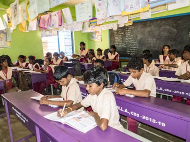PUDUCHERRY, İNDİA - Aralık 2018. Devlet okulunda üniformalı tanımlanamayan mutlu sınıf arkadaşları evde oturup kitap okuyor. Fakir gençlerin okul portresi arkadaşlığın keyfini çıkarıyor..