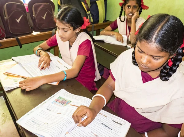 PUDUCHERRY, İNDİA - Aralık 2018. Tanımlanamayan, devlet okulu üniformalı, sandalyeye oturmuş kapalı alanda kitap okuyan ciddi sınıf arkadaşları. Okul gençlerinin portresi.
