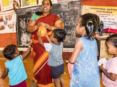 Puduchery, Hindistan - Aralık yaklaşık, 2018. Zavallı okul öncesi öğretmeni ve grubu çocuklar çocuklar kız okulda sadece birkaç ahşap oyuncak oyunları ile şaka yapıyordum. Okulda yoksulluk
