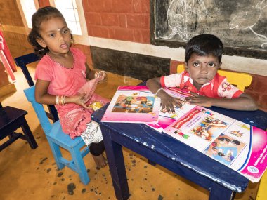 Puduchery, Hindistan - Aralık yaklaşık, 2018. Kimliği belirsiz sevimli küçük çocuk, Erkek, kitap okuma bir kreş oturan kız. Hükümet okul öncesi kötü koşulları.