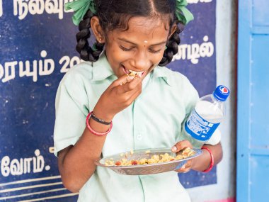 Puduchery, Hindistan - Aralık yaklaşık, 2018. Pirinç levha yeme tanımlanamayan yakışıklı tatlı gülümseyen Hintli kız açık havada, portresi. Yoksul insanların olsalar bile neşeli kavramı.
