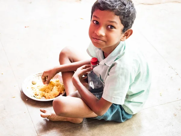 Puduchery, Hindistan - Aralık yaklaşık, 2018. Pirinç levha yeme tanımlanamayan yakışıklı tatlı gülümseyen Hintli çocuk açık havada, portresi. Yoksul insanların olsalar bile neşeli kavramı.