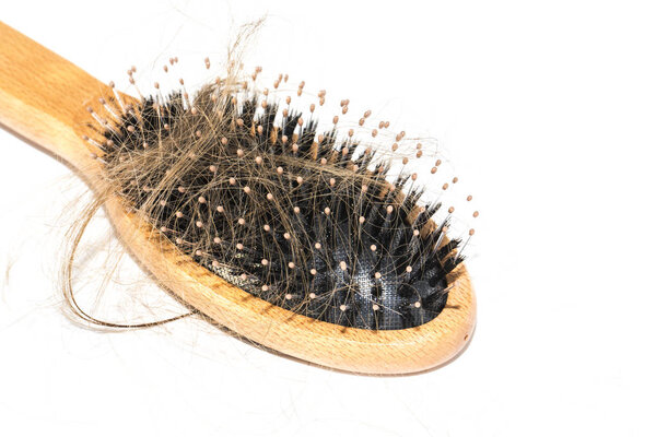 Hair loss on washbasin. Long brown hair with wood brush on white basin in the bathroom. Healthcare concept