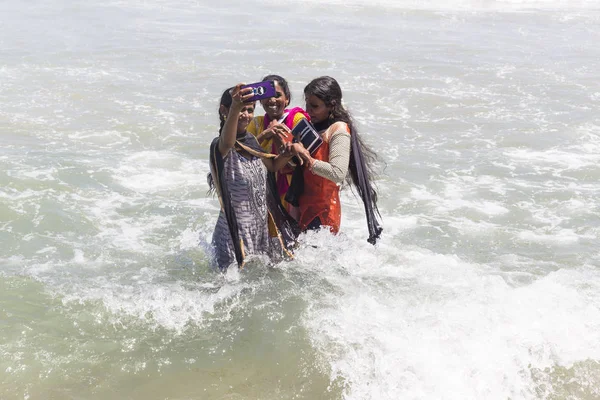 MASI MAGAM FESTIVAL, PUDUCHERY, PONDICHERY, TAMIL NADU, INDIA - 1 de marzo de 2018. Mujeres indias no identificadas bañándose en el mar, tomando selfies con teléfono, en la playa — Foto de Stock