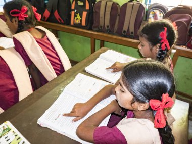 Çocuk arkadaş portresi okul içinde sandalyelerde oturan kitap ile okuyan sınıf arkadaşları. Dostluk zevk okul çocuklar