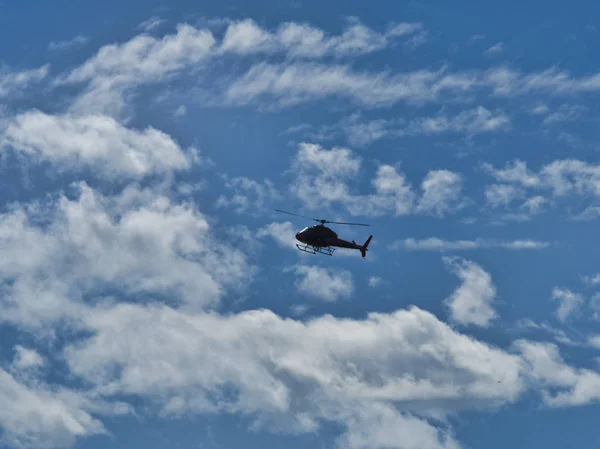 Летит вертолет самолет в голубом небе с облаками — стоковое фото