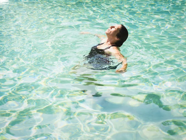 Mulher deitada em águas límpidas na praia tropical. bela menina madura deitado e desfrutando na água e relaxante — Fotografia de Stock