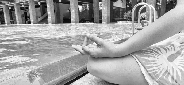 40 jonge vrouw mediteren met uitzicht op rustige groen blauw water, close-up van haar handen en gekruiste benen in de lotuspositie — Stockfoto