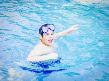 Aquapark'taki yüzme havuzunda mutlu genç çocuk. Sevimli çocuk tatilde eğlenceli zaman sahip.