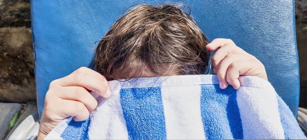Um adolescente chateado, cobre o rosto com toalha de praia. close-up de rosto e mãos. retrato de um adolescente frustrado — Fotografia de Stock