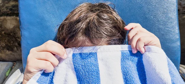 Een tiener jongen boos, bedekt zijn gezicht met strandlaken. Close-up van gezicht en handen. Portret van een gefrustreerde tiener — Stockfoto