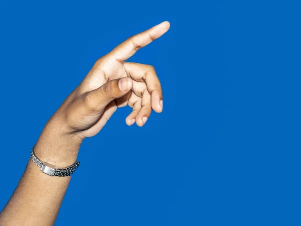Close up of a young indian woman hand pointing finger as touching screen, isolated on blue background.