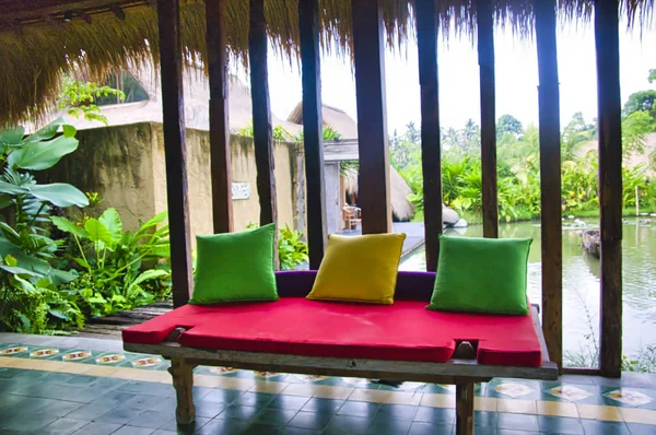 A teakwood Balinese-style batavia bench next to a lake. Cosy luxury travel concept Stock Image