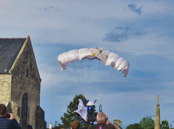 Ein roter Fallschirm hängt am blauen Himmel. Militärfallschirmspringer landet mit Big Bag bei sainte mere l 'eglise, Frankreich, Normandie — Stockfoto