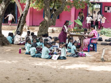 Çocuk arkadaş grup kız erkek sınıf arkadaşları okul oyun alanında açık zeminde oturan kitap ile eğitim.