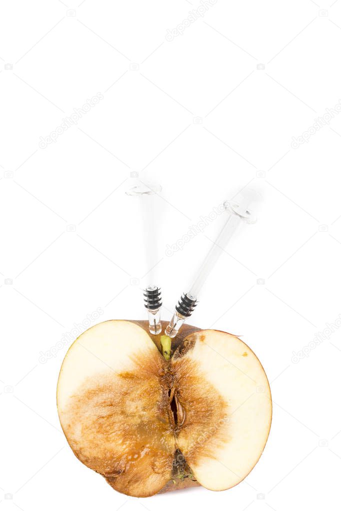Close up Boring trace of a codling moth Cydia Pomonella, in a half wormy apple. On white background. With syringe. Concept non organic and genetically modified organism