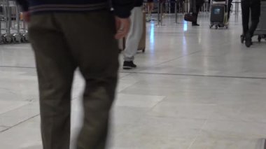 Paris, Fransa - Aralık 2018. Kimliği belirsiz yolcular uçuştan önce Paris havaalanı koridorunda yürüyorlar. Bacakları ve bavulları kapatın.