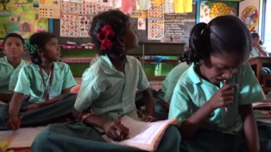 Puducherry, Tamil Nadu, Hindistan - Aralık 2018. Tanımlanamayan yoksul Hintli öğrenci. Yerel bir devlet okulunda üniformalı. Öğretmeniyle İngilizce öğreniyor..