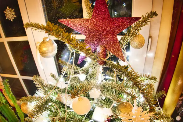 Julgran med röd glänsande stjärna och vitt och guld leksaker i inredningen. — Stockfoto