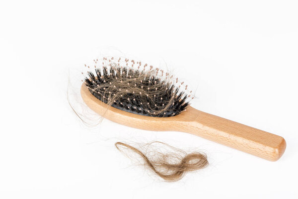 Wood hairbrush on white background. Close-up with long brown hair