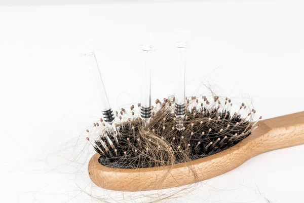 Trä hår borste på vit bakgrund. Närbild med långt brunt hår och spruta för att illustrera hår avfall behandling medicin — Stockfoto