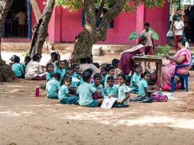 PUDUCHERRY, İNDİA - Aralık 2018. Kimliği belirsiz bir grup çocuk kız arkadaş devlet okulu üniformalı sınıf arkadaşları yerde oturup dışarıda kitaplarla çalışıyorlar..