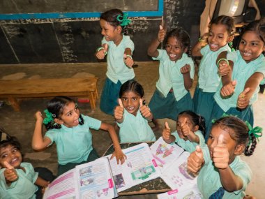 PUDUCHERRY, İNDİA - Aralık 2018. Devlet okulu üniformalı kimliği belirsiz mutlu sınıf arkadaşları yerde oturup kapalı alanda kitap okuyorlar. Okul gençlerinin portresi arkadaşlık duygusunu seviyor..