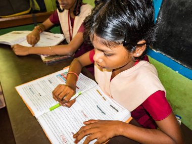 PUDUCHERRY, İNDİA - Aralık 2018. Tanımlanamayan, devlet okulu üniformalı, sandalyeye oturmuş kapalı alanda kitap okuyan ciddi sınıf arkadaşları. Okul gençlerinin portresi.