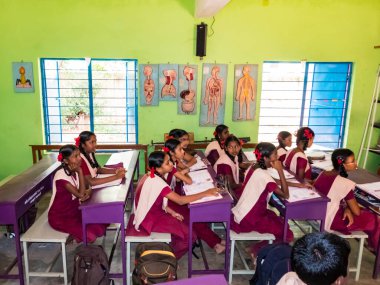 PUDUCHERRY, İNDİA - Aralık 2018. Devlet okulunda üniformalı tanımlanamayan mutlu sınıf arkadaşları evde oturup kitap okuyor. Fakir gençlerin okul portresi arkadaşlığın keyfini çıkarıyor..