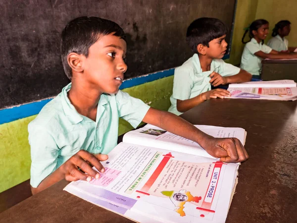 PUDUCHERRY, İNDİA - Aralık 2018. Tanımlanamayan, devlet okulu üniformalı, sandalyeye oturmuş öğretmenle birlikte kapalı alanda kitap okuyan ciddi sınıf arkadaşları. Okul gençlerinin portresi.