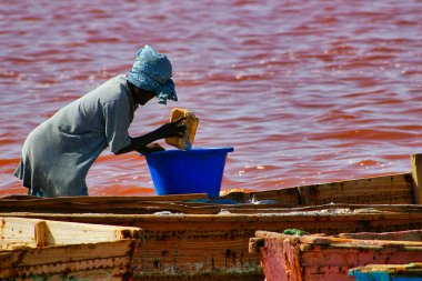SENEGAL, AFRICA - MARSCH Circa, 2016. Kimliği belirsiz siyah Afrikalı kadın ve erkek Senegal 'deki Pembe Göl' de çiftçinin denizden tuz almaya geldiği yerde. Çok zor bir iş. Canlı renkler