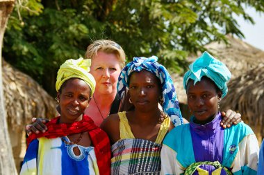 SENEGAL, AFRICA - Mart 2019. Kimliği belirsiz Fransız turist ve Afrikalı kadınlar çalılıklarda. Çok utangaç.