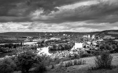 Fransa 'da Rouen yakınlarındaki Seine Nehri' ne yakın küçük bir köye geniş açıdan geniş bir manzara. Güzel bir kır manzarası, turistik bir yer. Güzel ışıklar, bulutlu gökyüzü. Dramatik bir atmosfer. Siyah ve beyaz