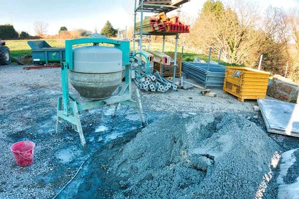 Cement machine close to bunch of gravel stones with red bucket of water. Construction working