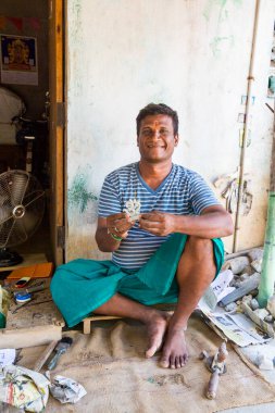 PUDUCHERRY, Hindistan - Mart 2019. Tanımlanamayan Hintli heykeltıraş olgun bir adam küçük Ganesh Tanrı heykelini oyuyor. Küçük dükkanının yanında oturuyor..
