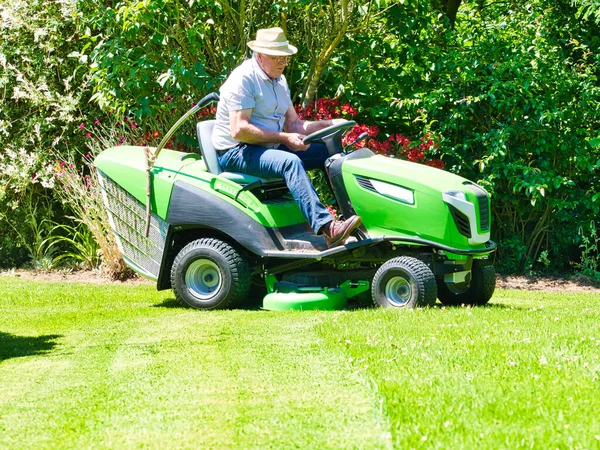 Starší Muž Let Řídí Sekačku Trávu Zahradě Květinami Zelená Bílá — Stock fotografie