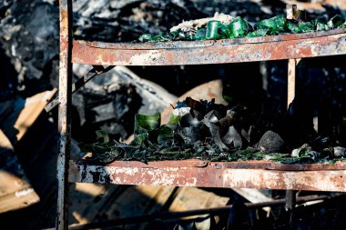 Şiddetli yangın felaketinin ardından yanan siyah molozlarla yanan kundaklama sonrası raflardaki hasarlı süpermarket cam plastik şişeleri sigorta araştırması için bekletiliyor. Doymuş karşıtlık etkisi dramatik atmosfer