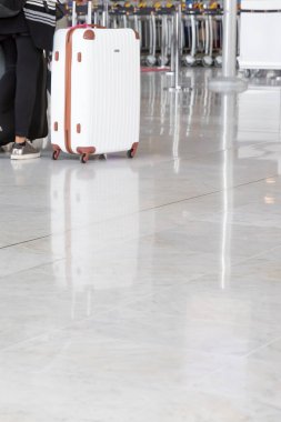 Seyahat bavulu olan erkek ya da kadın gezgin tatil işi konsepti için havaalanı koridorunda yürüyüş yapıyor. Boş havaalanı salonu