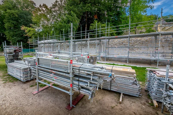 Piles of new square hollow section galvanused steel pipes and tubes with anti rust oil coating. Applications in scaffoldings, trolleys, cabins, fencing, etc. Background is a wall with scaling — Stock Image Piles New Square Hollow Section Galvanused Steel Pipes Tubes Rust Stock Photo